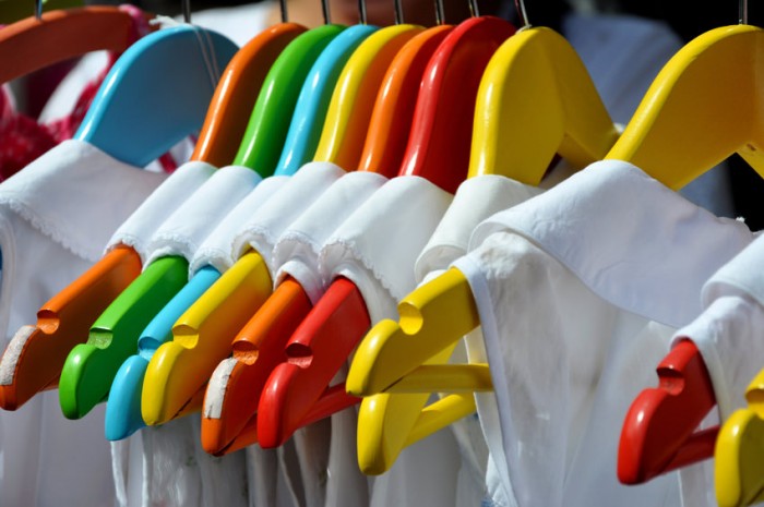 Vegane, weiße Kleidung auf bunten Bügeln